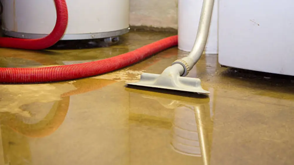 Wet vacuum with a red hose on a flooded floor