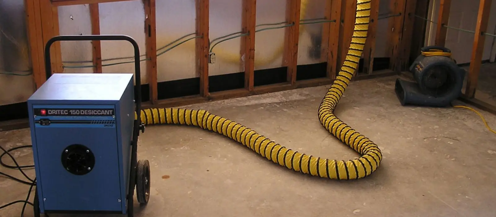 Dehumidifier with a drying duct running in a room with opened lower walls